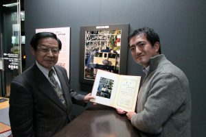 鉄道友の会賞に輝いた加藤篤史氏と関専務理事。受賞作品の前で記念撮影